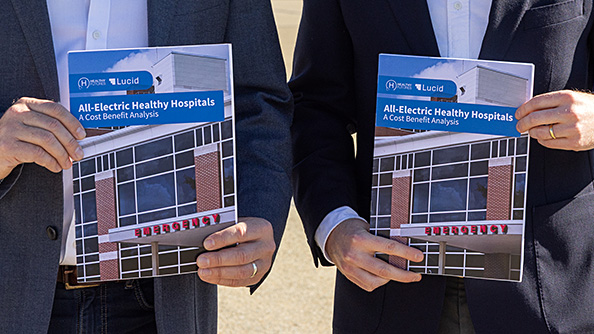 Two people holding copies of the Healthy Hospitals report.